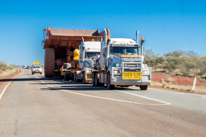 Two prime movers pulling and one pushing this mining giant along the road.